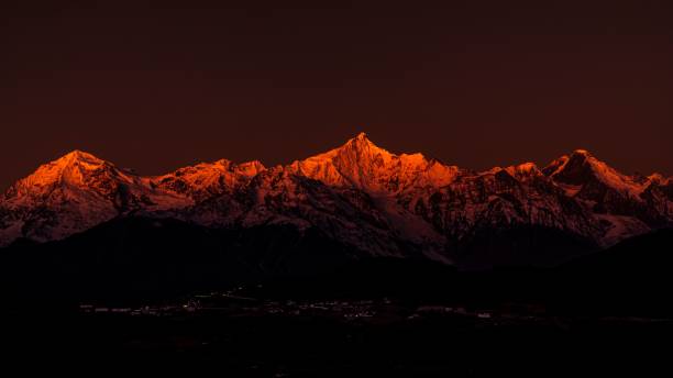 beeindruckende nachtlandschaft mit einem leuchtend roten himmel, der über dem kalten meili schneeberg in tibet drapiert ist - alpenglühen stock-fotos und bilder