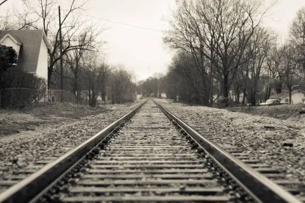 A picturesque rural village with a vintage railroad track running through the center, greyscale