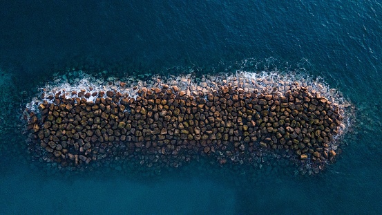 An aerial view of the breakwater in a tranquil blue water