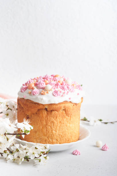 istock Traditional Easter sweet bread or cakes with white icing and sugar decor, colored eggs and cherry blossom tree branch over white table. Various Spring Easter cakes. Happy Easter day. Selective focus. 1477798806