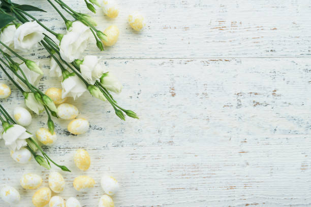 istock Happy Easter. Easter eggs and rabbit in green basket on white old wooden table with white and yellow roses. Spring Happy Easter holiday card.  Easter background with copy space. Top view. 1477800578