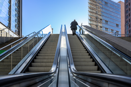 Rear View Of Man Standing On Escalator Against Building At Postdamer Platz Berlin