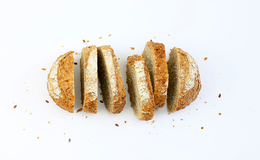 Slices of wholemeal bread with seeds on a white background. Directly above.