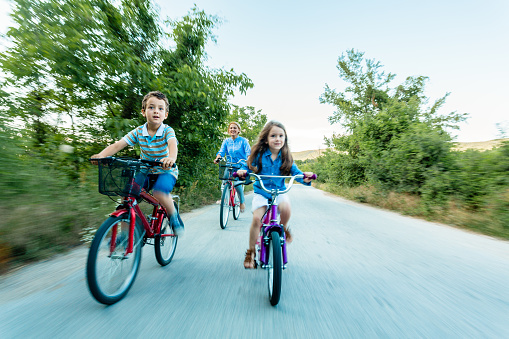 Mother and children riding bicycle together and having fun in the nature. Motion blur.