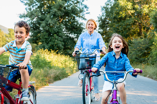 Mother and children riding bicycle together and having so much fun in the nature