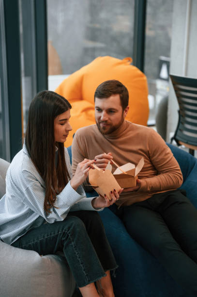 istock Sitting and talking. Office workers are in the rest zone is having a break and eating food from paper eco boxes 1477809491