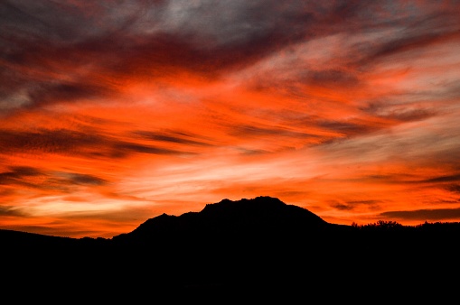 An awe-inspiring sunset in spectacular red and orange tones illuminating the silhouette of Granite Mountain in Prescott, Arizona