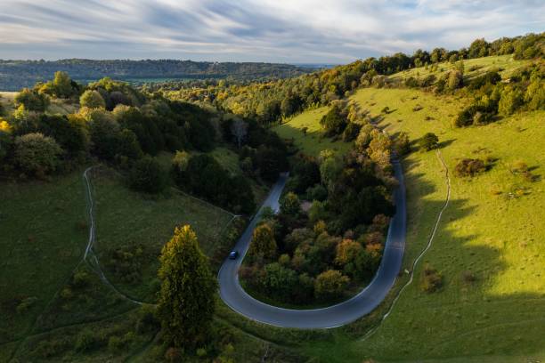 istock Car driving up along a winding road, surrounded by lush hilly terrain 1477810323
