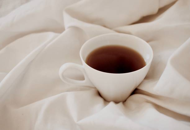 istock White ceramic cup of tea on a bed of white sheets 1477810364