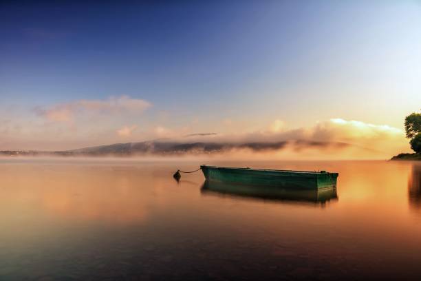 istock Idyllic scene showing a small boat drifting across a tranquil lake at sunset 1477814244