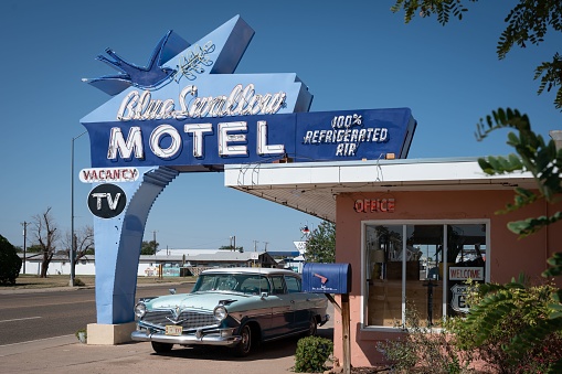 Tucumcari, United States – August 17, 2022: Classic Blue Swallow motel on historic Route 66 with a blue Hudson Hornet car at the door