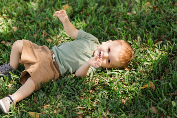 A Happy 15-Month-Old Cuban-American Baby Boy Playing & Collecting Small Cut Tree Branches During Family Yard Work Outdoors on the Front Lawn on a Warm South Florida Spring Day in 2023, Tree Trimming Before Hurricane Season Starts un feliz bebé cubanoamericano de 15 meses jugando y acostado en el césped durante el trabajo familiar en el jardín al aire libre en el jardín delantero en un cálido día de primavera del sur de florida en 2023, podando árboles antes de que comience l