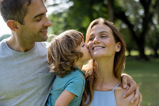 Loving Brazilian family outdoors with a boy kissing his mother - lifestyle concepts