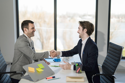 Two businessmen shaking hands after making an agreement in the office.