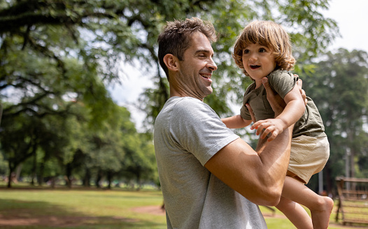 Loving Brazilian father playing with his son at the park and looking very happy - lifestyle concepts