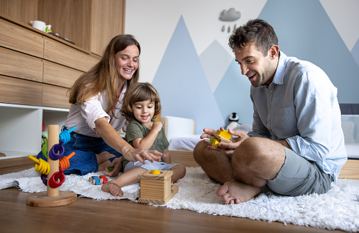 Happy boy learning while playing with toys at home with his parents - family lifestyle concepts