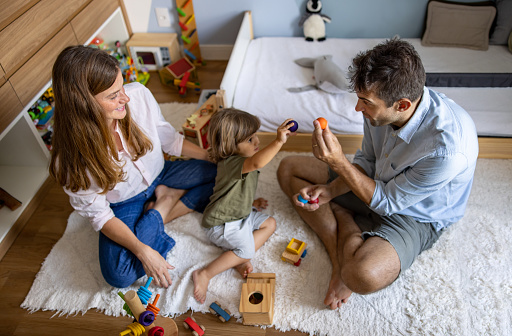 Brazilian parents teaching their child at home while playing with toys - lifestyle concepts