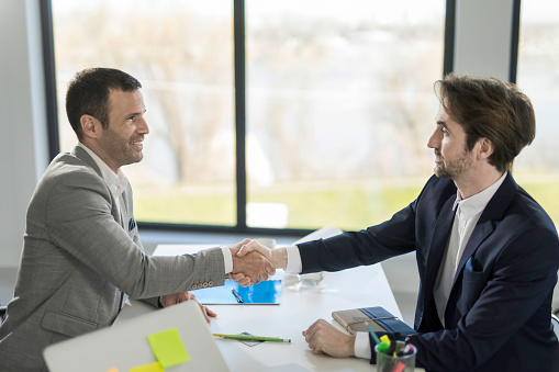 Two businessmen shaking hands after making an agreement in the office.