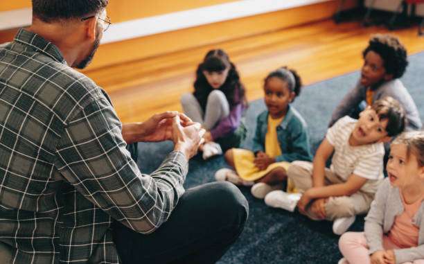 istock Educator teaches an elementary school class. Man talking in front of a group of children 1477820899