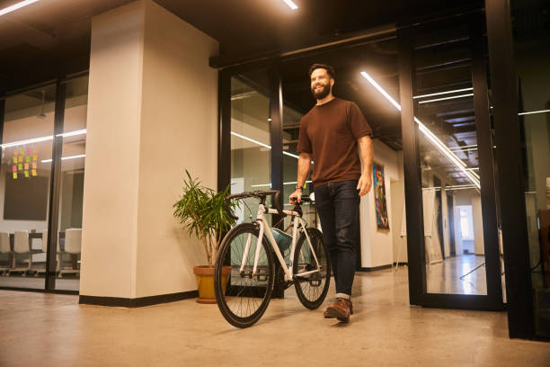 istock Smiling young designer walking into an office with his bike 1477823905