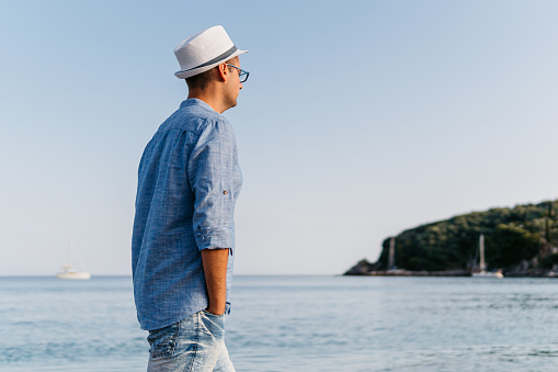 Handsome young man walking on the beach in Parga, Greece.