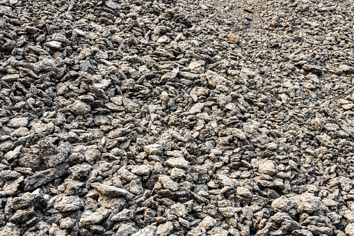 Background view: Heaps of bits and pieces of asphalt stones taken from demolished roads are deposited for reuse as material for further road repairs.