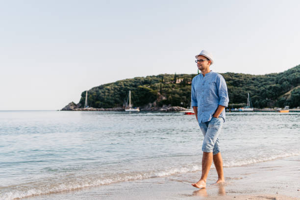 istock Young Man Walking Barefoot On The Beach In Greece 1477824992