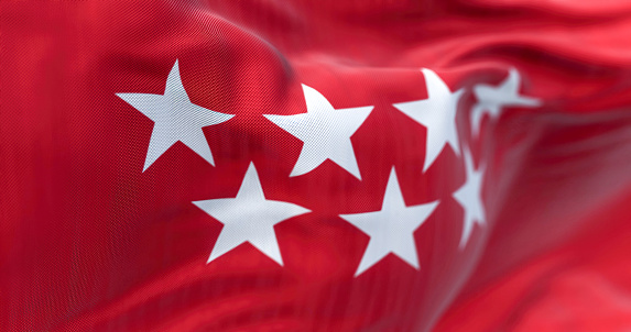 Detail of the Community of Madrid flag waving in the wind. Crimson red with seven silver five-pointed stars. 3d illustration render. Selective focus. Rippled textile