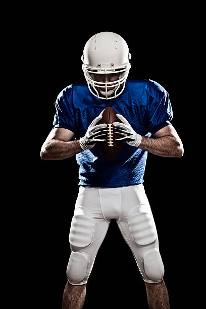 Football Player with a ball 03 Football player with a ball in the hands, looking to the ball. Photo made in studio with black background and hard light. american football player studio stock pictures, royalty-free photos & images