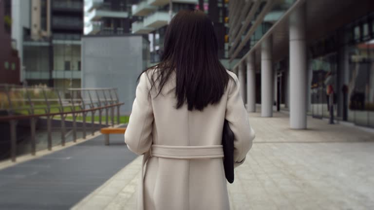 Back View of Elegant Businesswoman Walking in the Morning to her Office. Female Project Manager Walking in the Street, Ready to Start the Work Day, Considering Innovative Ideas for Company Meeting