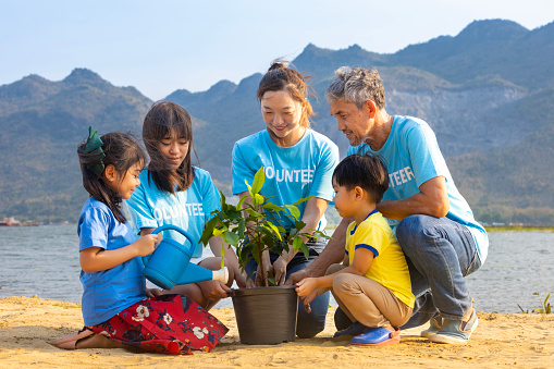 Team of volunteer worker group teaching children to planting tree in charitable social work on forest rewilding NGO work for fighting climate change and global warming in the coastline habitat concept