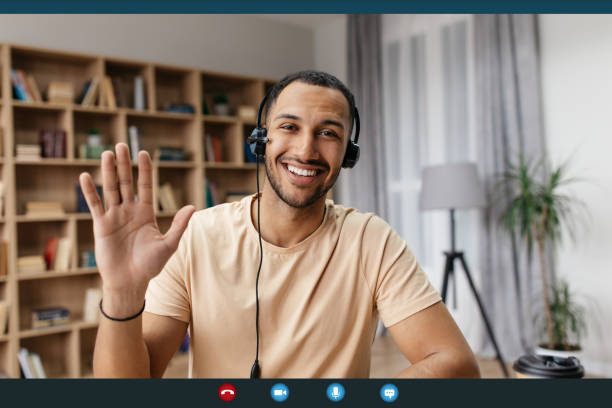 Videocall screenshot of cheerful arab man in headset having web conference, waving hand at camera and smiling Videocall screenshot of cheerful arab man in headset having web conference, waving hand at camera, gesturing hello and smiling, enjoying online communication, webcam view man video call pov stock pictures, royalty-free photos & images