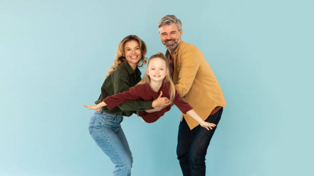 istock Parents Holding Daughter Posing Having Fun Over Blue Background, Panorama 1477838856