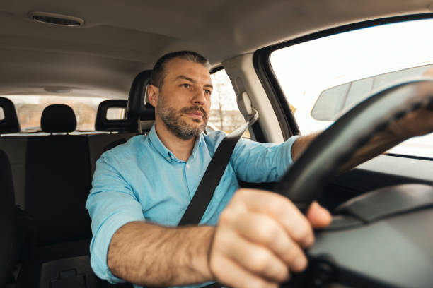 istock Man Driving New Car Sitting Inside Automobile Riding In City 1477841113