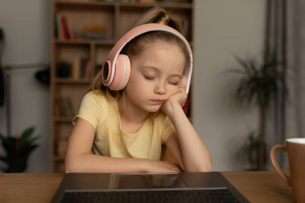 屋内のオンライン授業中にラップトップの前で寝ている女子高生 - six animals audio ストックフォトと画像