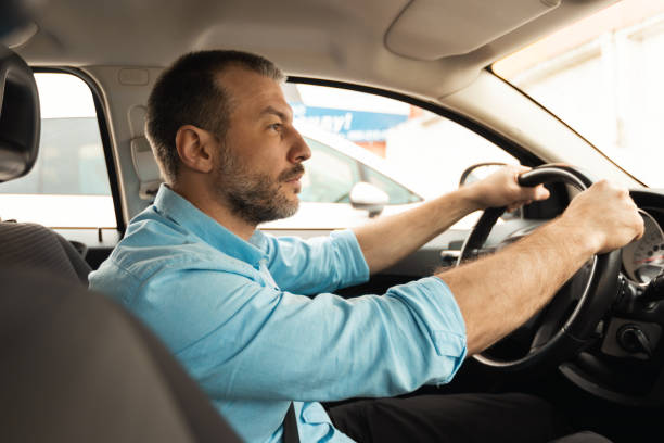 istock Side View Of Male Driver Driving Car Sitting Inside Auto 1477841395