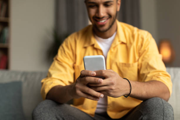 istock Happy young black male using smartphone, browsing internet, posting in social media at home, selective focus 1477841625