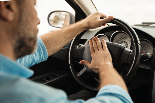 Hombre adulto conduciendo un automóvil y tocando la bocina, presionando la bocina photo