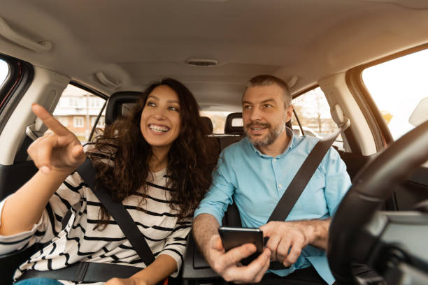 istock Happy couple driving car and using cell phone 1477841661