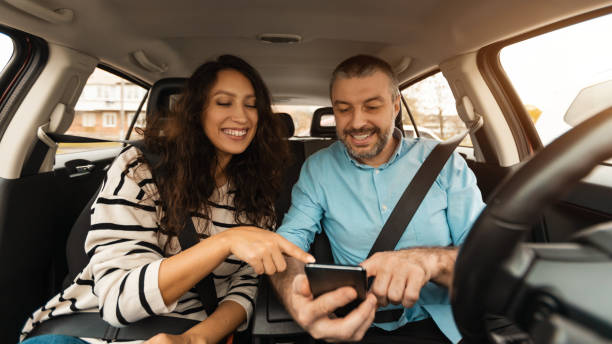 istock Happy couple driving car and using cell phone 1477841662