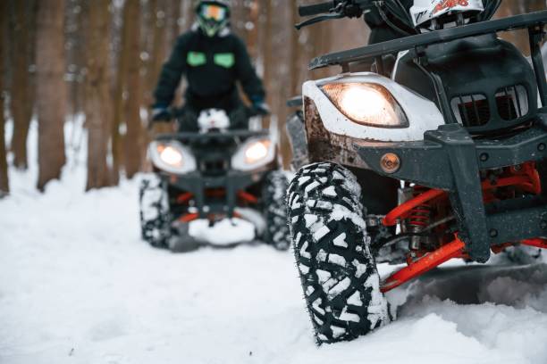 na zaśnieżonej ziemi. dwie osoby jadą quadem w zimowym lesie - off road vehicle quadbike 4x4 adventure zdjęcia i obrazy z banku zdjęć