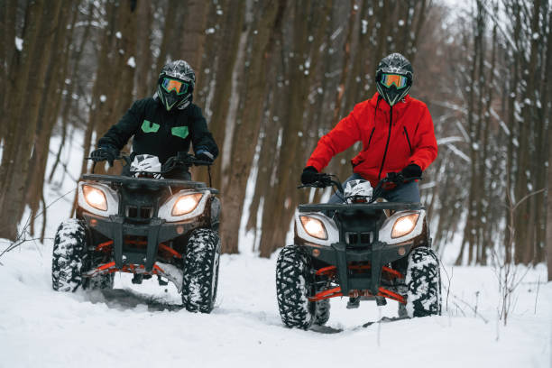 istock Conception of active recreation. Two people are riding ATV in the winter forest 1477843744