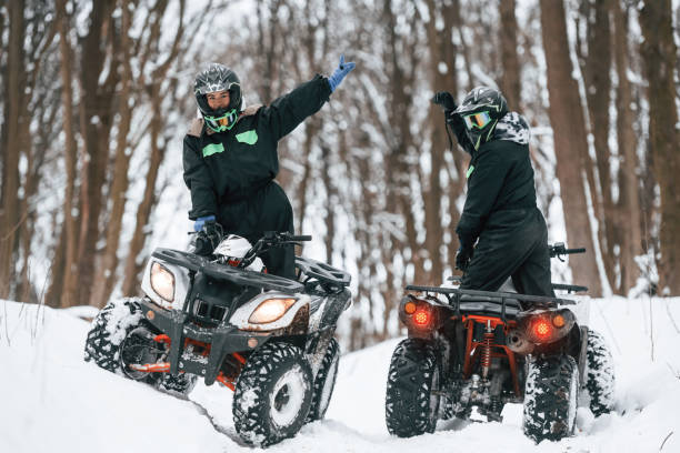 istock Making gestures. Two people are riding ATV in the winter forest 1477843761