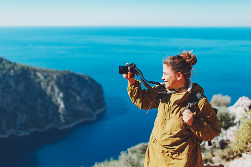 Young adult woman looking at Butterfly valley and making photo with photo camera