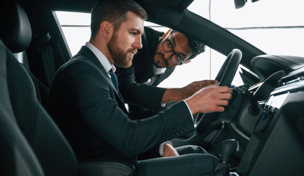 istock Man showing automobile interior to the customer 1477846435