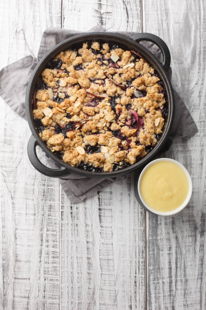istock Swedish pie Smulpaj baked with apples and blueberries close-up in a pan. Vertical top view 1477846588