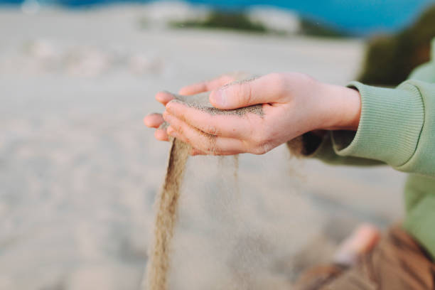 istock Boy playing in sand dunes, close up of hands with sand 1477846872