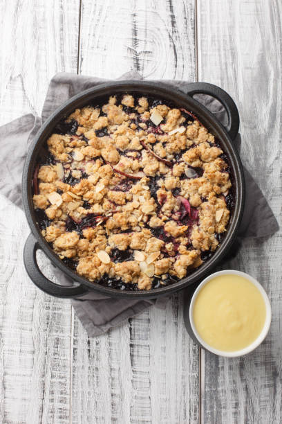 istock Swedish Fruit Crumble Pie Smulpaj with home made vanilla sauce closeup. Vertical top view 1477847098