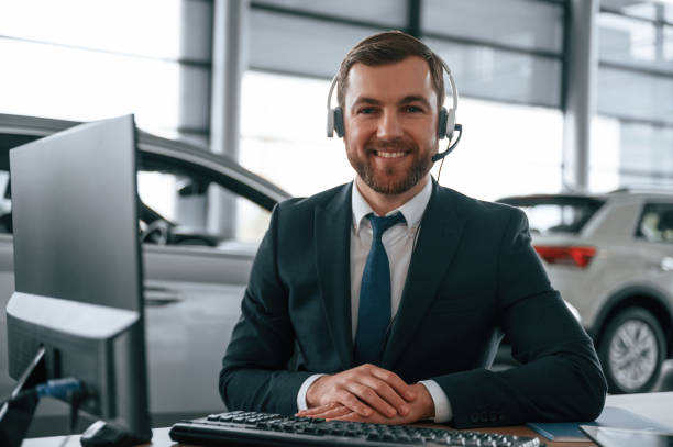 istock Man is sitting and working in the car showroom 1477848986