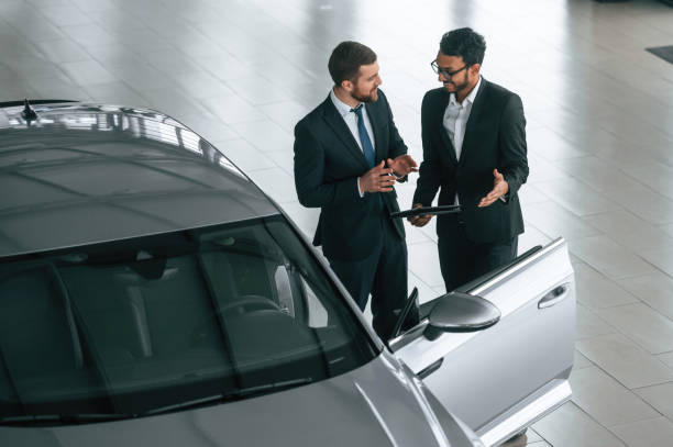 vista superior. el hombre está consultando al cliente en la sala de exposición de automóviles - india car people business fotografías e imágenes de stock